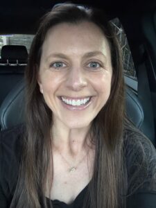 OL smiling, but tension in her eyes and neck. Eyes look a bit like a deer in the headlights.